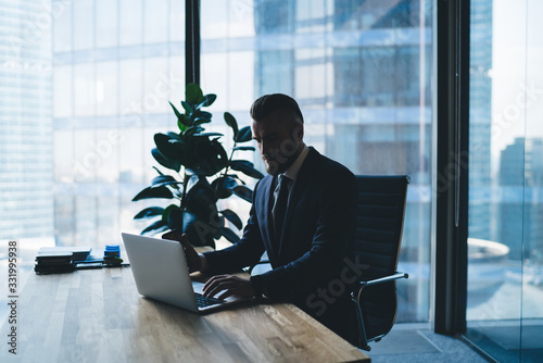 Bearded boss using laptop in office