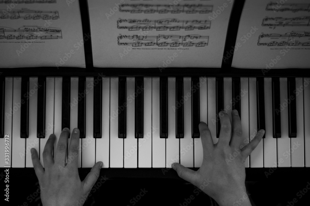 Fototapeta premium Black and white photography of hands playing piano and readingscores