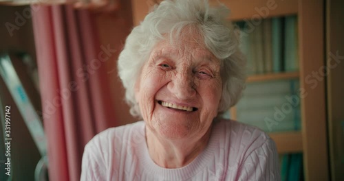 Portrait of a happy elderly woman with full white hair looking at the camera and smiling with white teeth. photo