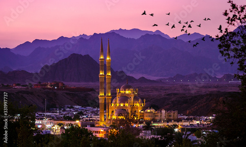 Al-Sahaba Mosque with night lights - arabic architecture and monuments in Sharm el Sheikh, Egypt. Ancient mosque of the old town at sunset with mountains silhouettes on skyline. photo