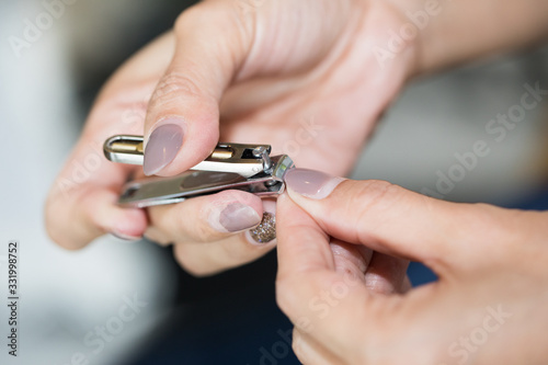 Woman cutting her nail close up.