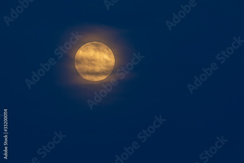 Yellow full moon with halo against a dark blue sky