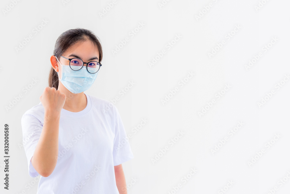 Portrait Asian young woman wears glasses and mask to protect against Coronavirus, girl show a fist encourage to fight contagious disease concept stop virus Covid 19 outbreak to win on white background Portrait Asian young woman wears glasses and mask to protect against Coronavirus, girl show a fist encourage to fight contagious disease concept stop virus Covid 19 outbreak to win on white background