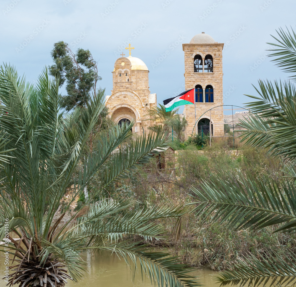 Ancient temple of St. John the Baptist in Greek monastery on the Jordan River with a Jordanian flag. Place of baptism of Jesus Christ and sacred site in the Holy Land for pilgrims of Christians.