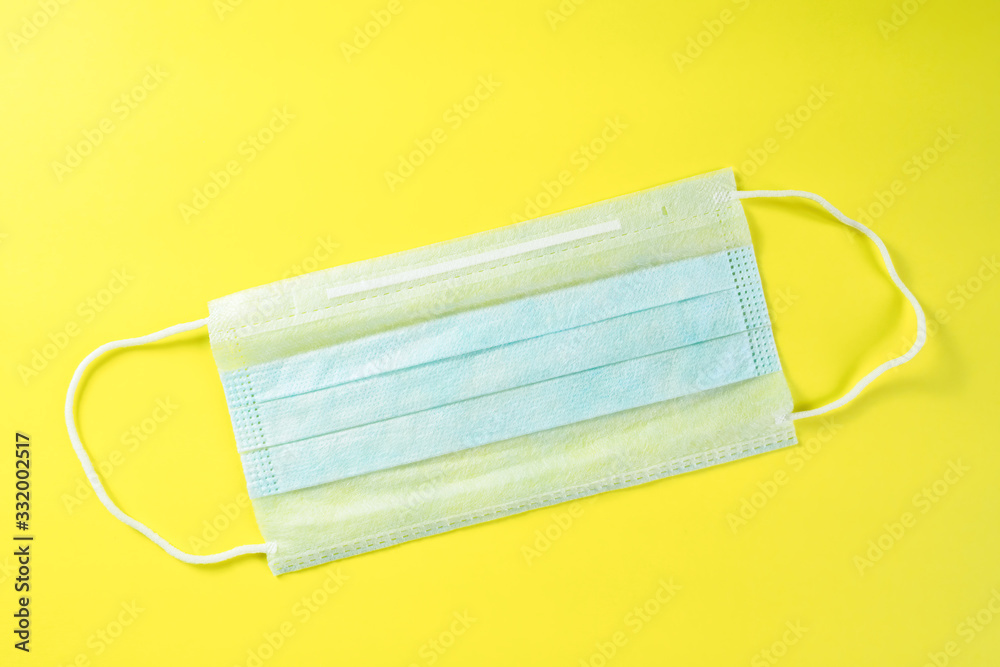 Disposable medical mask on yellow background. Concept of protection against coronavirus, allergies, flu. Surgical mask Disposable medical mask on yellow background. Concept of protection against coronavirus, allergies, flu. Surgical mask