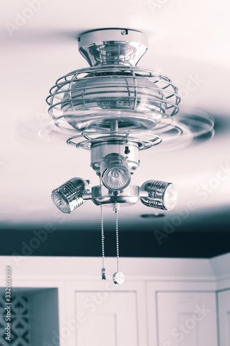 Ceiling fan light fitting with blades spinning in a kitchen. With colour toning