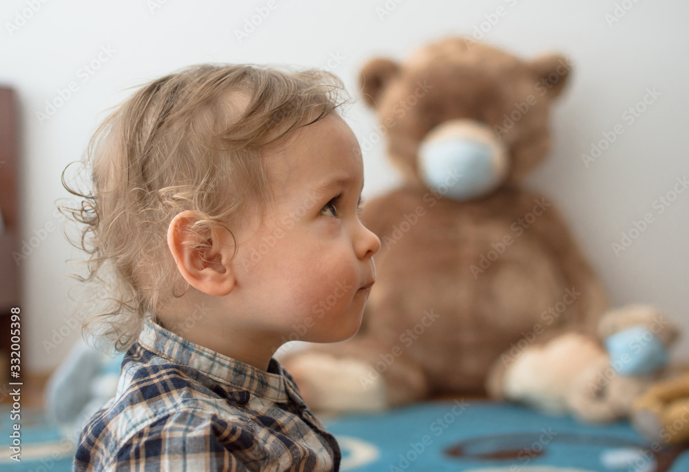 Child playing with his sick teddy bears wearing medical mask against viruses. Role playing, child playing doctor with plush toy. Children and flu, coronavirus illness concept. Selective focus Child playing with his sick teddy bears wearing medical mask against viruses. Role playing, child playing doctor with plush toy. Children and flu, coronavirus illness concept. Selective focus