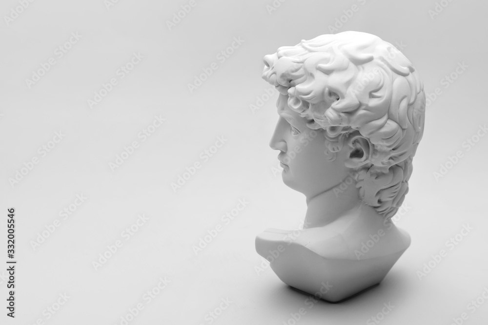 Gypsum statue of David's head. Michelangelo's David statue plaster copy on grey background with