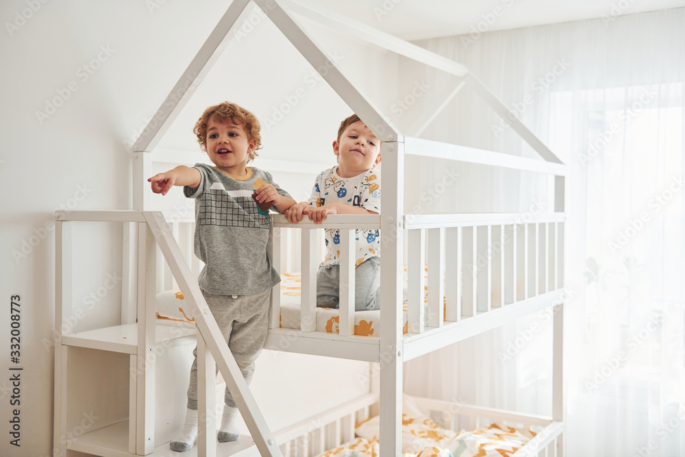 Two little boys resting and have fun indoors in the bedroom together Two little boys resting and have fun indoors in the bedroom together