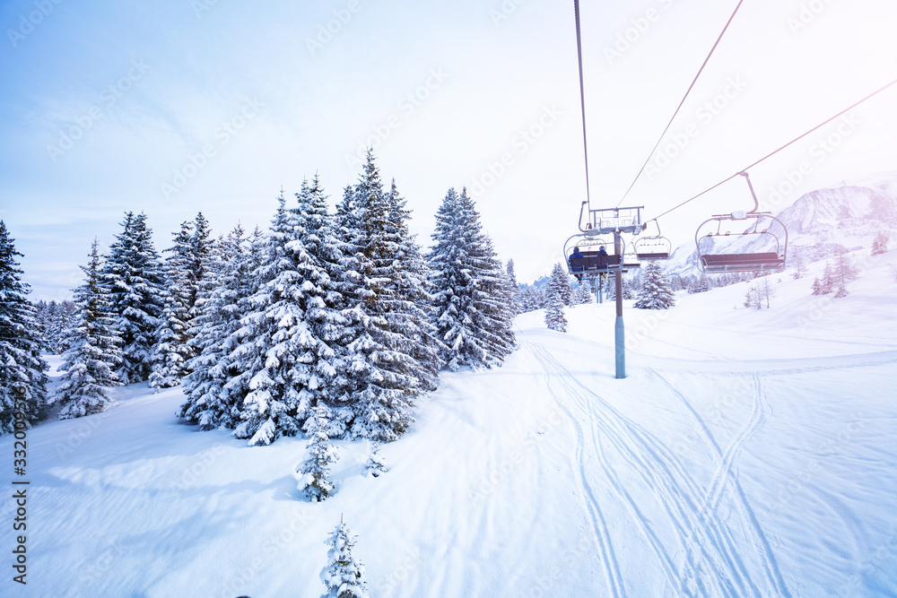 Winter fir and pine forest covered with snow after strong snowfall near ski lift on the mountain resort Winter fir and pine forest covered with snow after strong snowfall near ski lift on the mountain resort