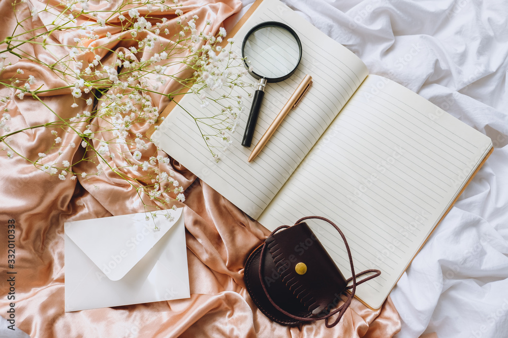 white gypsophila flowers with notebook and magnifying glass on the gold satin fabric white gypsophila flowers with notebook and magnifying glass on the gold satin fabric