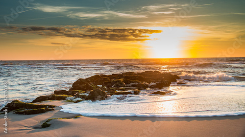 Sunrise over a foam-flecked jetty on Long Beach Island