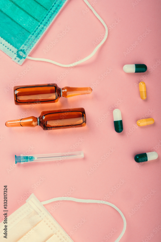 Protective face mask on pink background, pills, needle Protective face mask on pink background, pills, needle