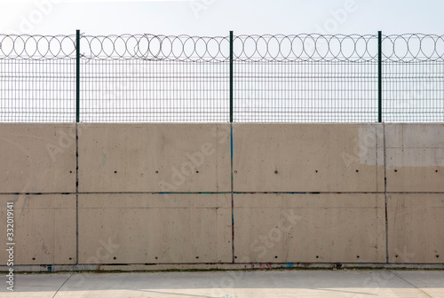  Razor wire with its sharp steel barbs on top of a concrete wall