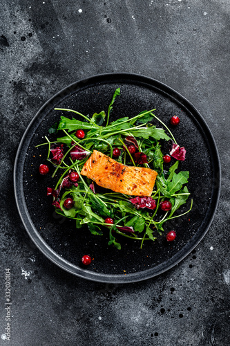 Seafood salad with salmon, arugula, lettuce and cranberries. Black background. Top view