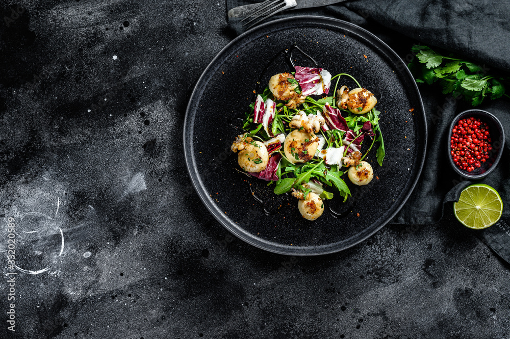 Thai salad with grilled squid and arugula. Black background. Top view. Copy space