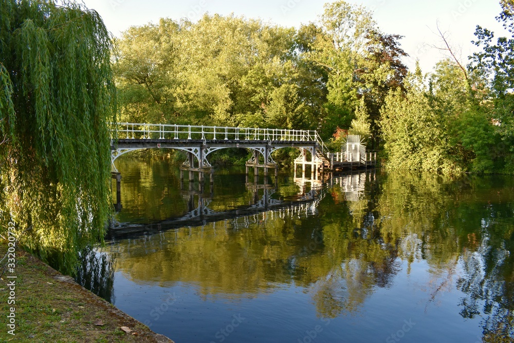An old white bridge over the river and green trees around
