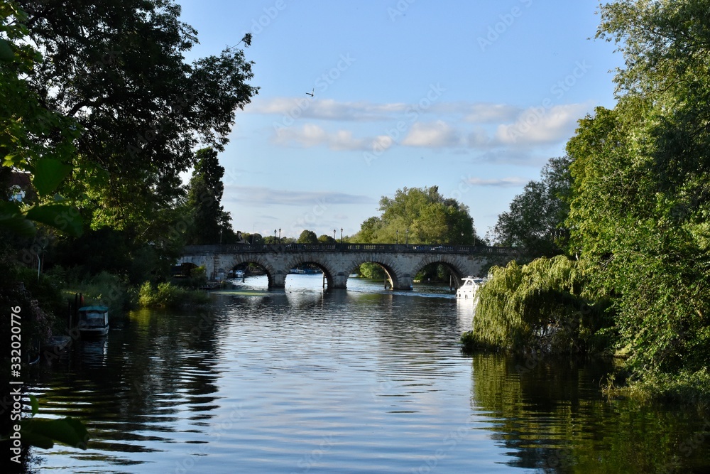 A river surrounded by trees and a brick bridge over it
