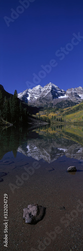 Panoramic view of autumn colors of Aspens reflecting in lake under Maroon Bells, Colorado, near Aspen