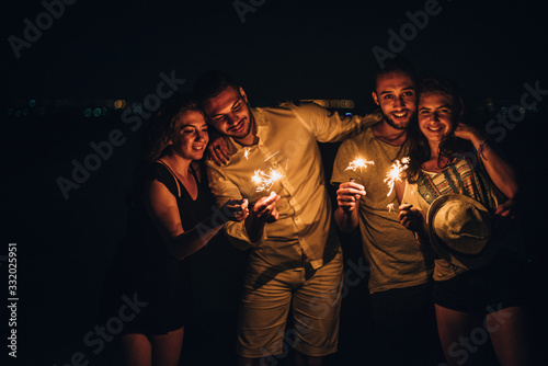 Party, holidays, nightlife and people concept - happy young pepole with sparklers