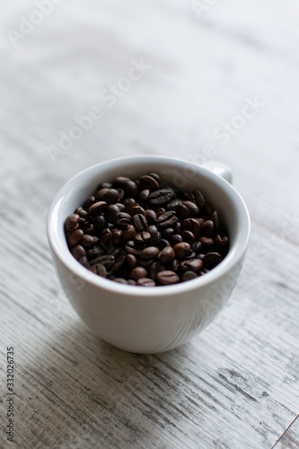 Coffee cup with coffee beans on white wooden table