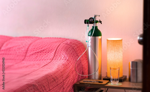 Oxygen cylinder with cannula next to the bed photo