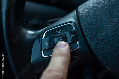 finger pressing answer button on steering wheel