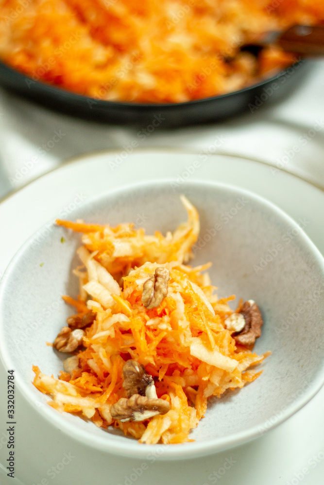 Freshly cut carrot salad with apple and chopped nuts served in a bowl 