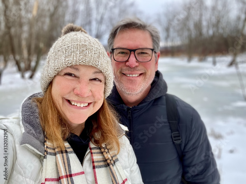 Happy middle aged couple taking a selfie outdoors in winter