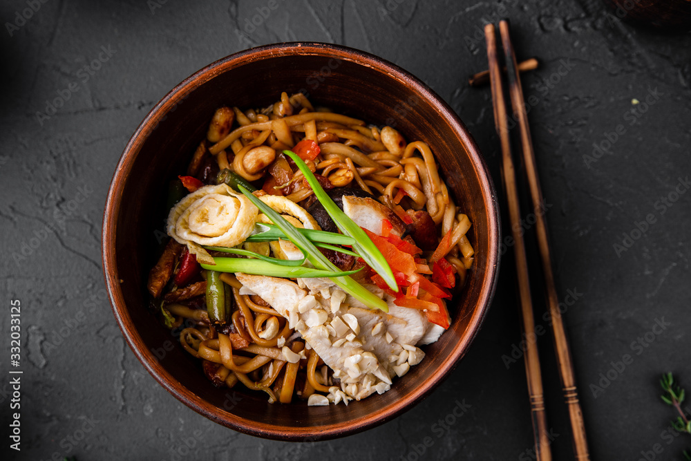 Chinese dishes in a clay plate on a black concrete background with ingredients for delivery Chinese dishes in a clay plate on a black concrete background with ingredients for delivery