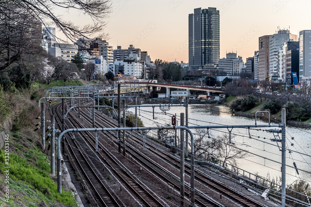 Fototapeta premium 夕方の東京都千代田区市ヶ谷の川沿いの線路と街並み