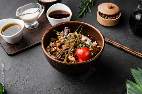 Chinese dishes in a clay plate on a black concrete background with ingredients for delivery