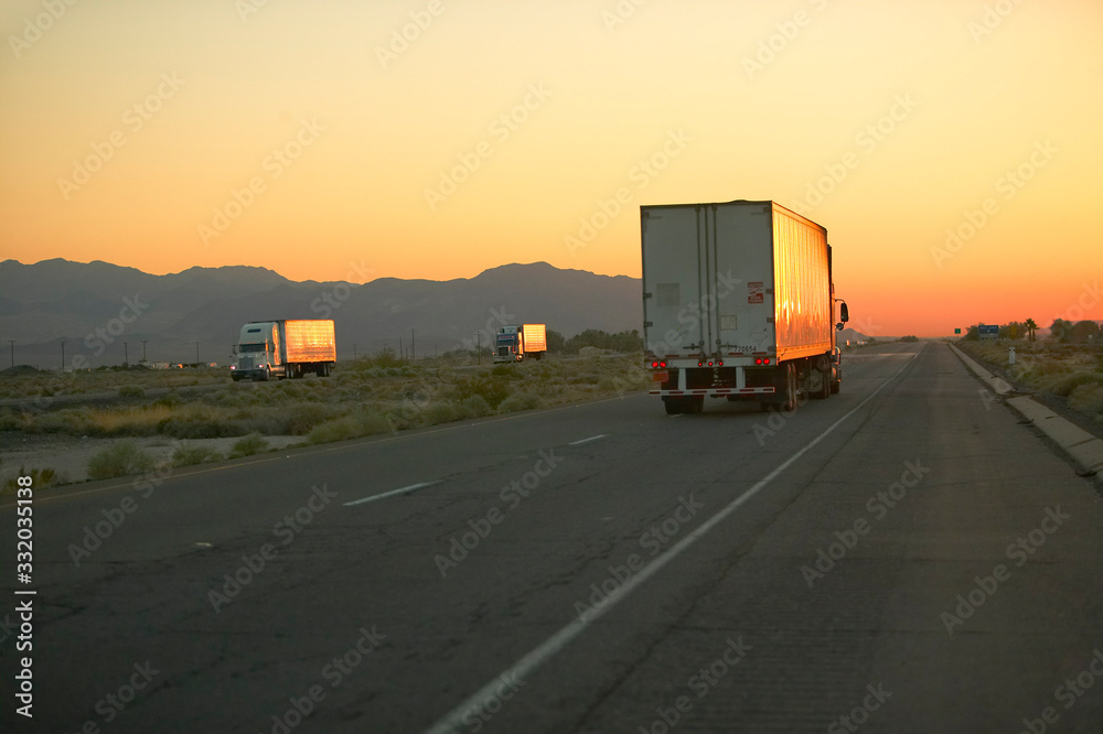 Φωτογραφία 18-wheeler semi-trucks at sunset hit the highway driving down Interstate Highway 15 between Los Angeles and Las Vegas Nevada