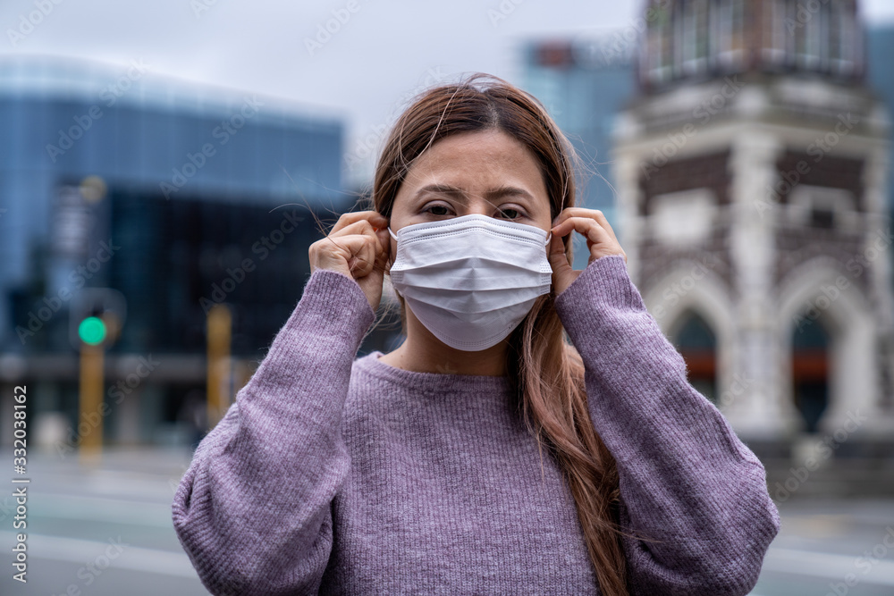 A beautiful middle aged Asian woman wearing a medical mask to protect from infection of virus, pandemic, outbreak and epidemic of disease in Christchurch city, New Zealand. Social distancing. A beautiful middle aged Asian woman wearing a medical mask to protect from infection of virus, pandemic, outbreak and epidemic of disease in Christchurch city, New Zealand. Social distancing.