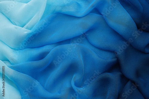 Blue draped silk fabric or scarf. Silk waves backdrop. photo