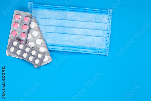 medical sick mask with a blister of pills on a blue background top view, medicl theme. photo