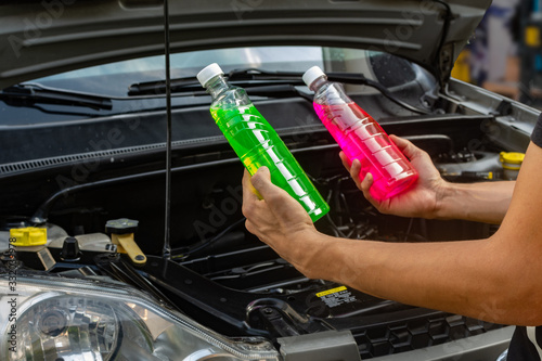  Topic of car repair shop: hands holding two products showing choice of pink or green coolant for cars. maintenance fluids or engine products. photo