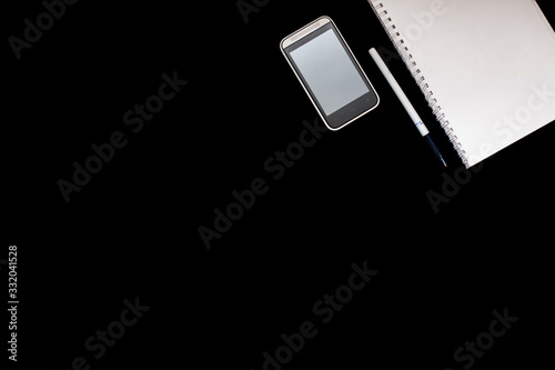 notebook on rings, mobile phone, pen on black background. Set for online training and Education and distance work. Flat lay. Top view