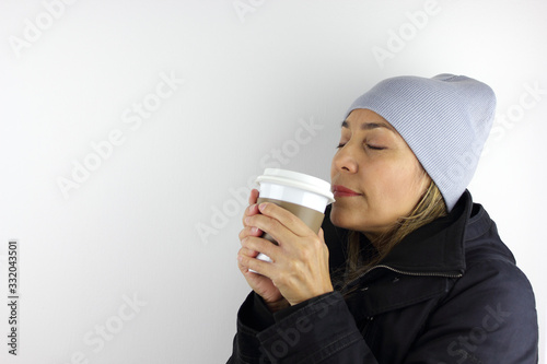 Beautiful woman with a keep cup of coffee. Enjoying the smell.