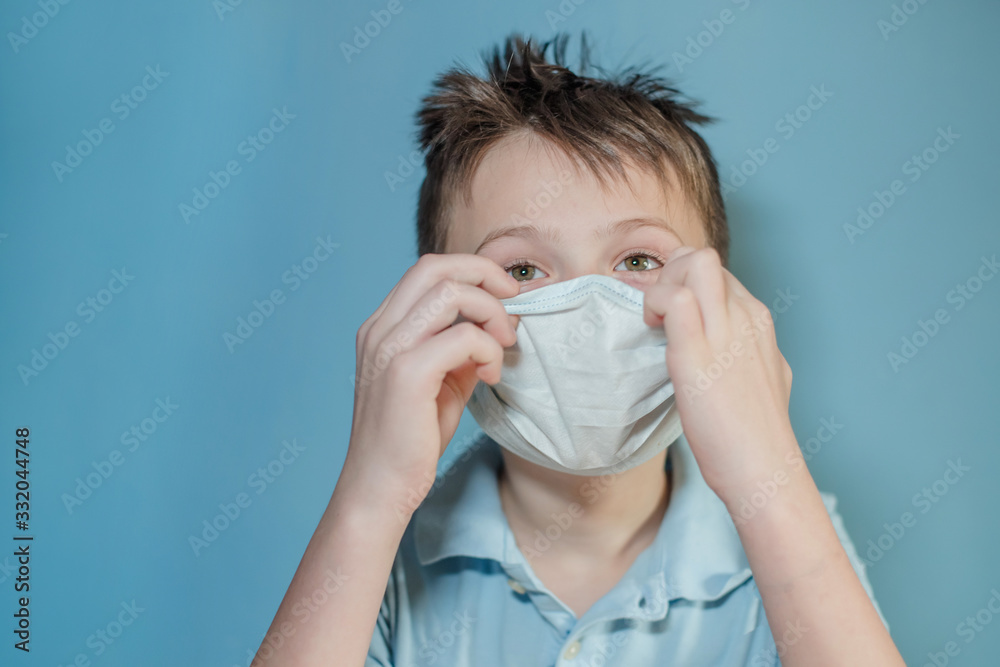 boy adjusts protective medical mask on face. Mistakes in dressing the mask. child touches face and carries virus. child with influenza or cold protected from viruses among patients with coronavirus