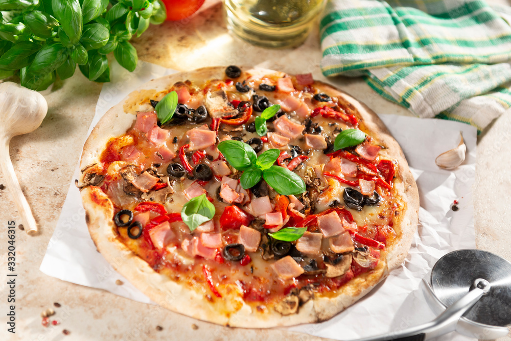 Tasty homemade pizza with ham, black olives and red pepper
