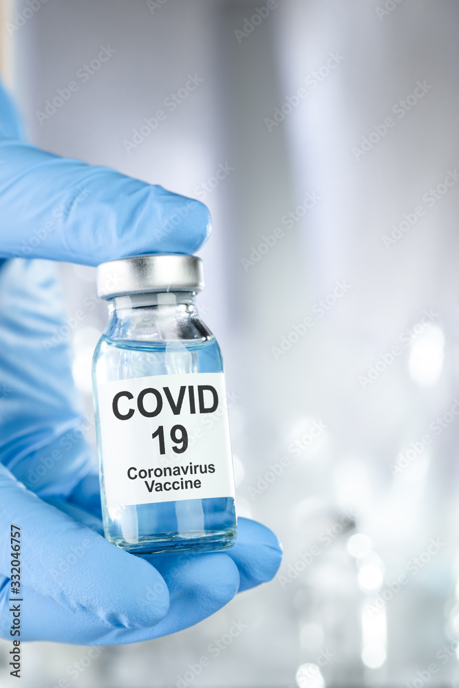 Healthcare cure concept with a hand in blue medical gloves holding Coronavirus, Covid 19 virus, vaccine vial Healthcare cure concept with a hand in blue medical gloves holding Coronavirus, Covid 19 virus, vaccine vial
