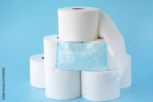  Toilet paper stacked rolls, medicine mask on a blue background. Items that buiyng in panic. Toilet paper crisis due to coronavirus COVID-19 quarantine. Copy space