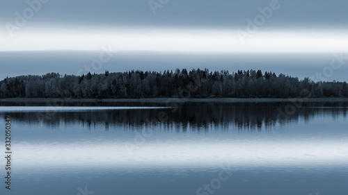 Serene landscape. Sunset on the lake, calm water surface, symmetrical reflection