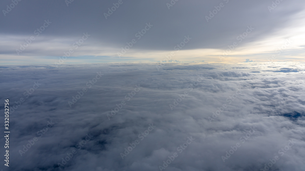 Skyscape view from clear glass window seat from aircraft to cloudscape, traveling on white fluffy clouds and vivid blue sky above the earth in a sunny day