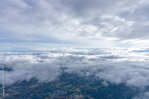 Skyscape view from clear glass window seat from aircraft to cloudscape, traveling on white fluffy clouds and vivid blue sky above the earth in a suny day