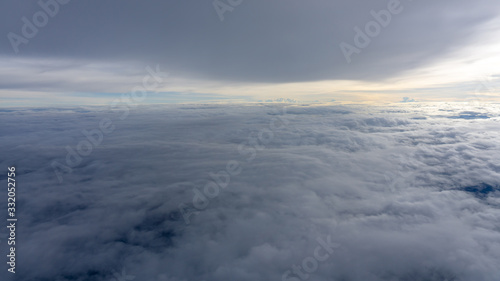Skyscape view from clear glass window seat from aircraft to cloudscape, traveling on white fluffy clouds and vivid blue sky above the earth in a sunny day © Arunee