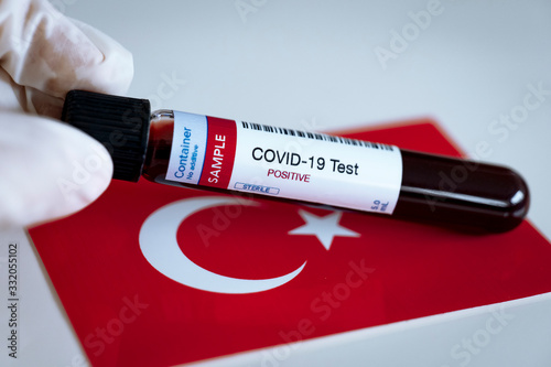 Testing for presence of coronavirus in Turkey. Tube containing a blood sample that has tested positive for COVID-19. Turkish flag in the background. photo