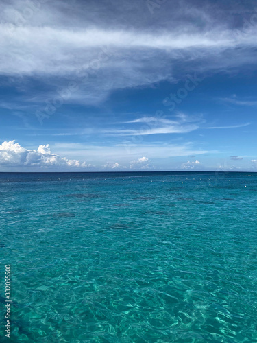 Landscape. View of the blue ocean from the line of the beach. Beautiful natural background. Horizon line of blue sea and sky with clouds. Vertical, cropped image, free space, nobody. Tourism concept.