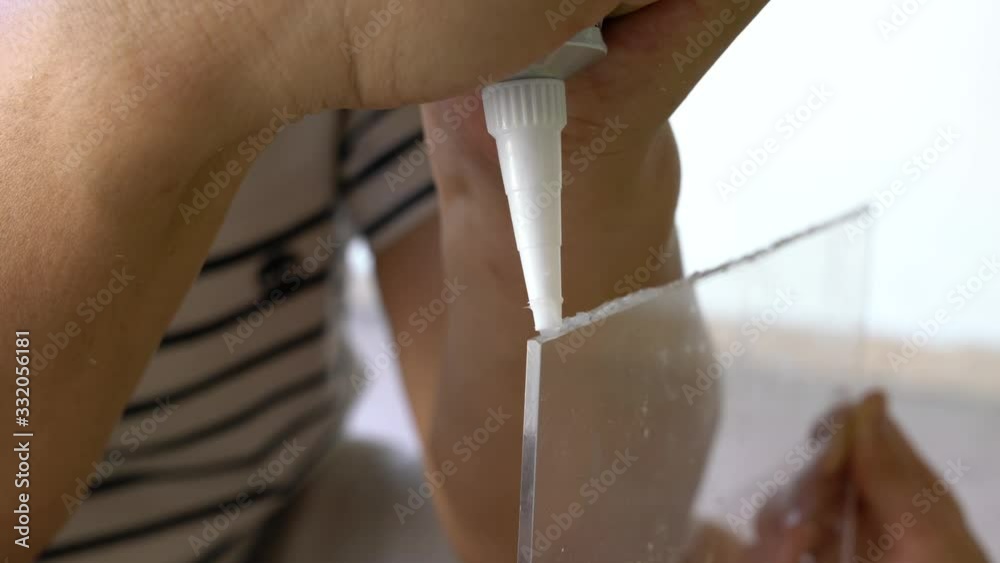 Apply glue on the skirting of an acrylic sheet. House improvement or do it yourself concept.